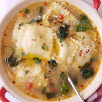 ravioli soup in a bowl with a spoon on the side.