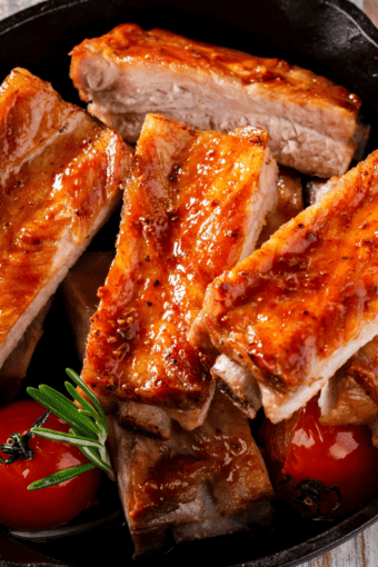 oven baked pork ribs served in a skillet with some veggies.