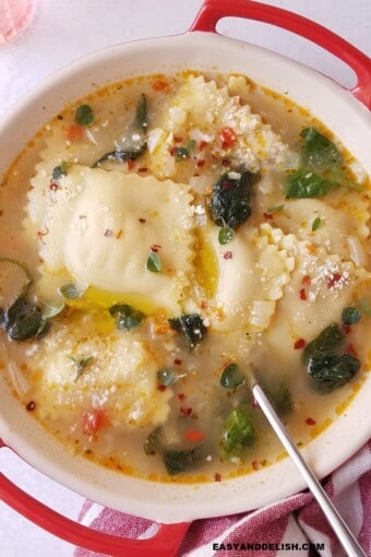 ravioli soup in a bowl with a spoon on the side.