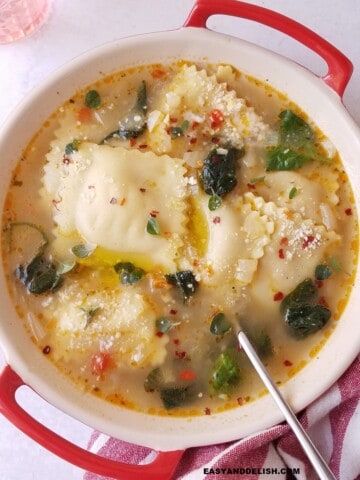 ravioli soup in a bowl with a spoon on the side.