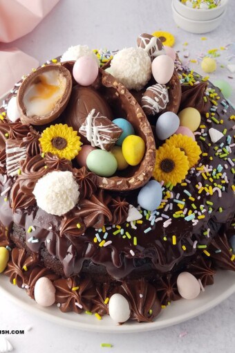 close up of an Easter bundt cake amde with sour cream and chocolate, topped with chocolate ganache, and decorated with Easter eggs.