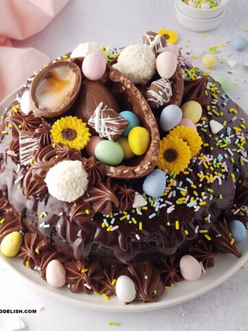 close up of an Easter bundt cake amde with sour cream and chocolate, topped with chocolate ganache, and decorated with Easter eggs.