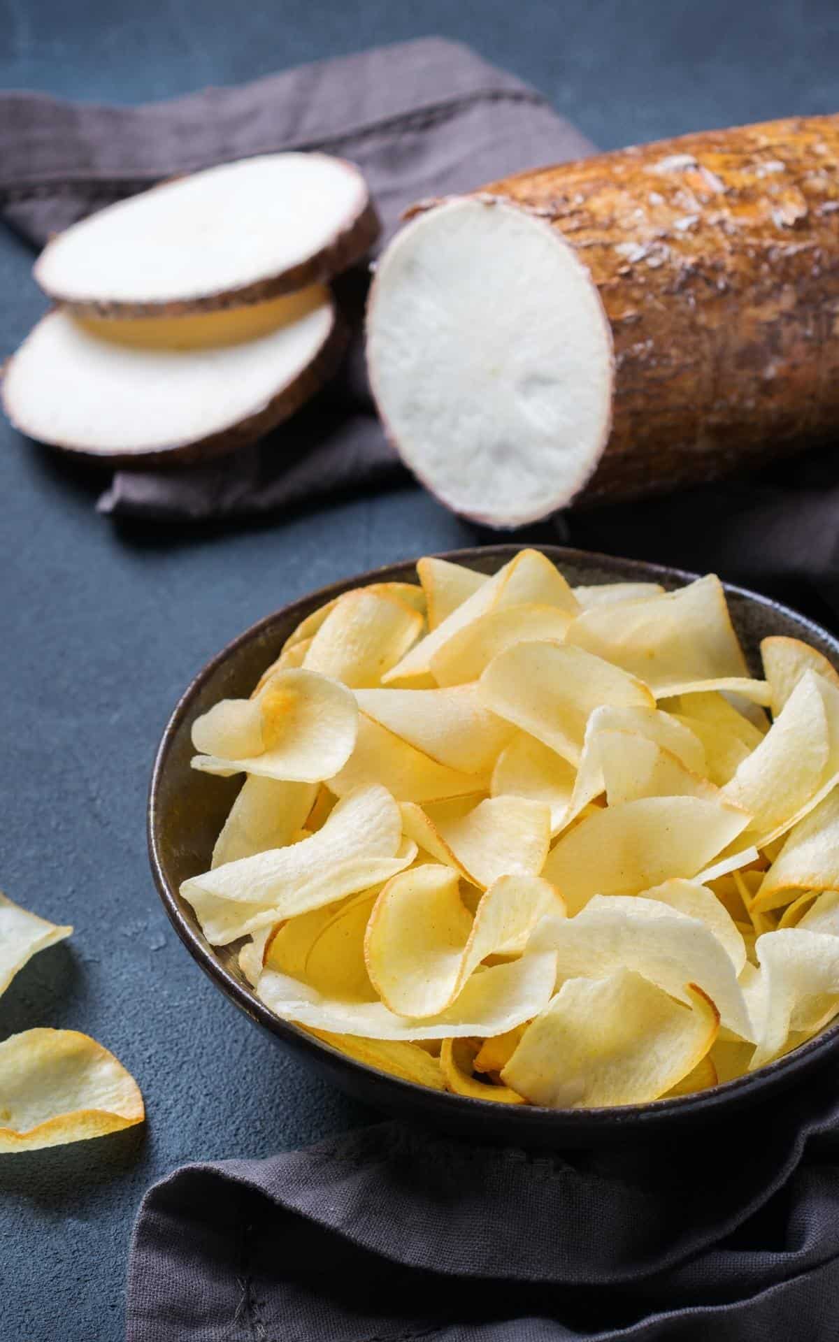 sliced cassava root and a bowl of yuca chips