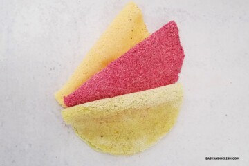 Three colorful Brazilian tapioca crepes without filling on a surface.