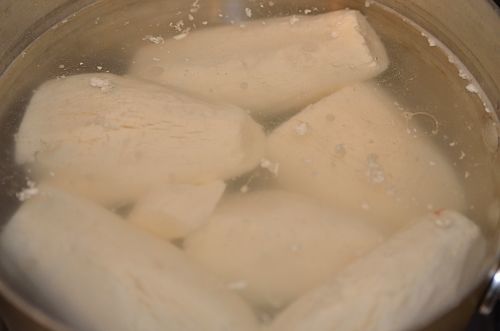 a pot of boiling water with pelled cassava root cooking.