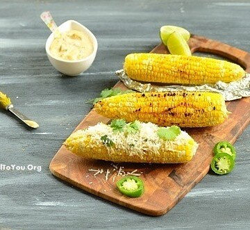 Grilled corn on the cob sitting on top of a wooden table