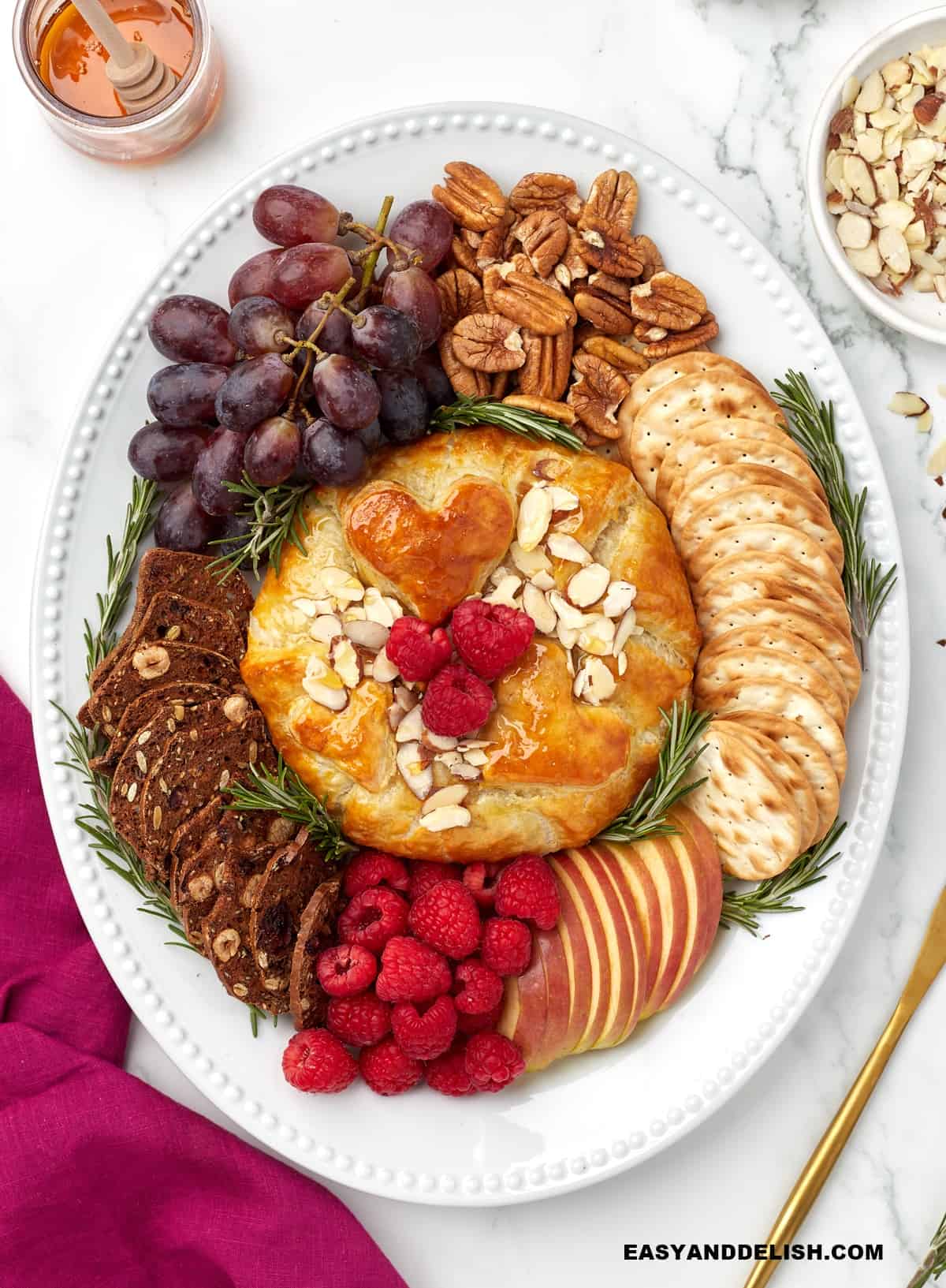 a appetizer platter with brie in puff pastry with garnishes around.