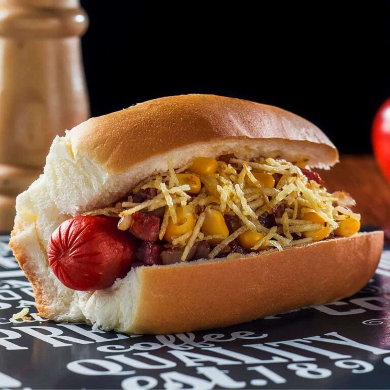 A Brazilian hot dog loaded with toppings on a table.