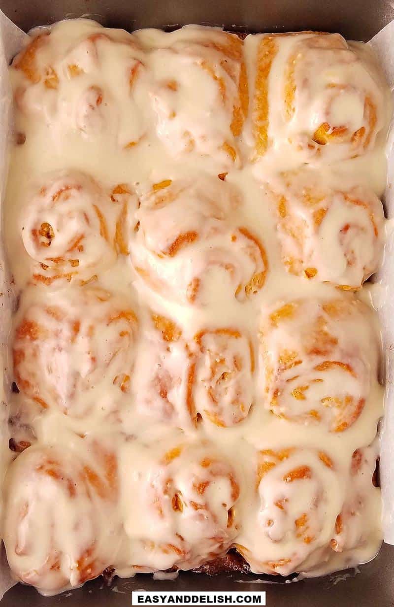 a baking pan full of baked coconut rolls with coconut frosting