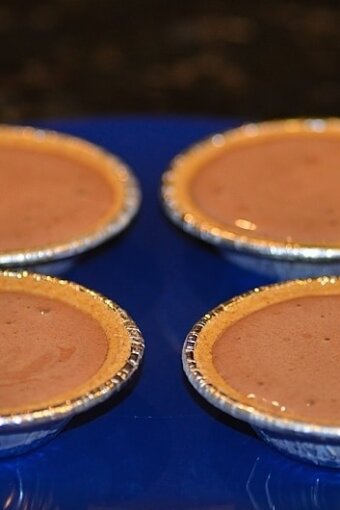 Four mini graham cracker pie crusts on a blue plate which are filled with the chocolate pudding ice cream mixture