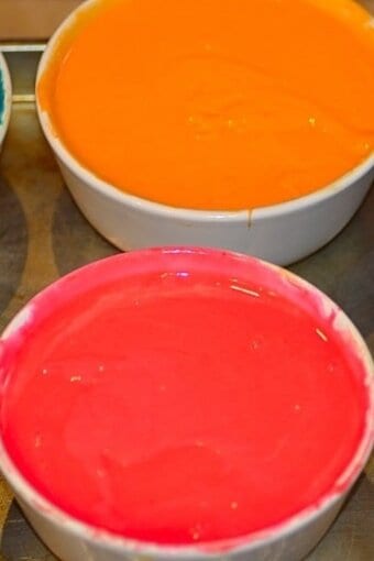 bowls of divided batter colored with several different shades of food coloring