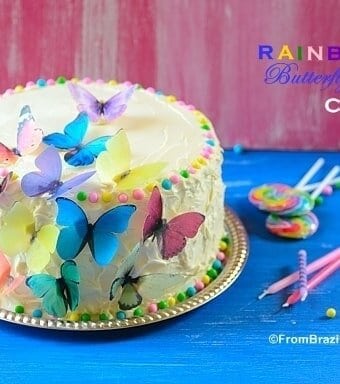 Rainbow cake sitting on top of a table and garnishes on the side to celebrate a birthday