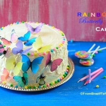Rainbow cake sitting on top of a table and garnishes on the side to celebrate a birthday