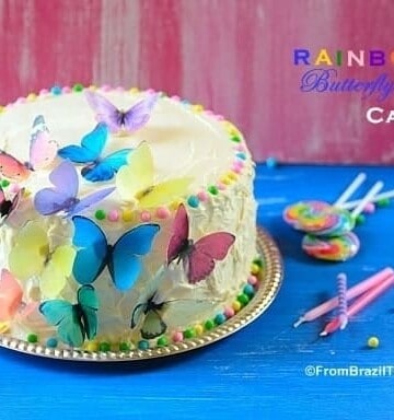 Rainbow cake sitting on top of a table and garnishes on the side to celebrate a birthday
