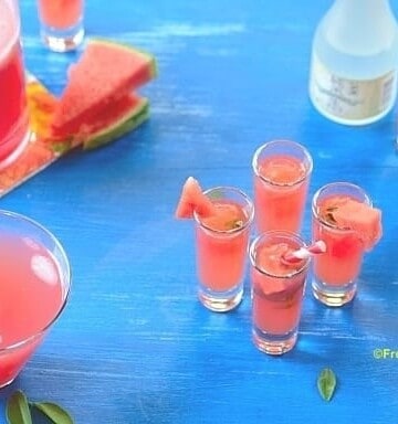 4 glasses of watermelon caipisake on a blue board