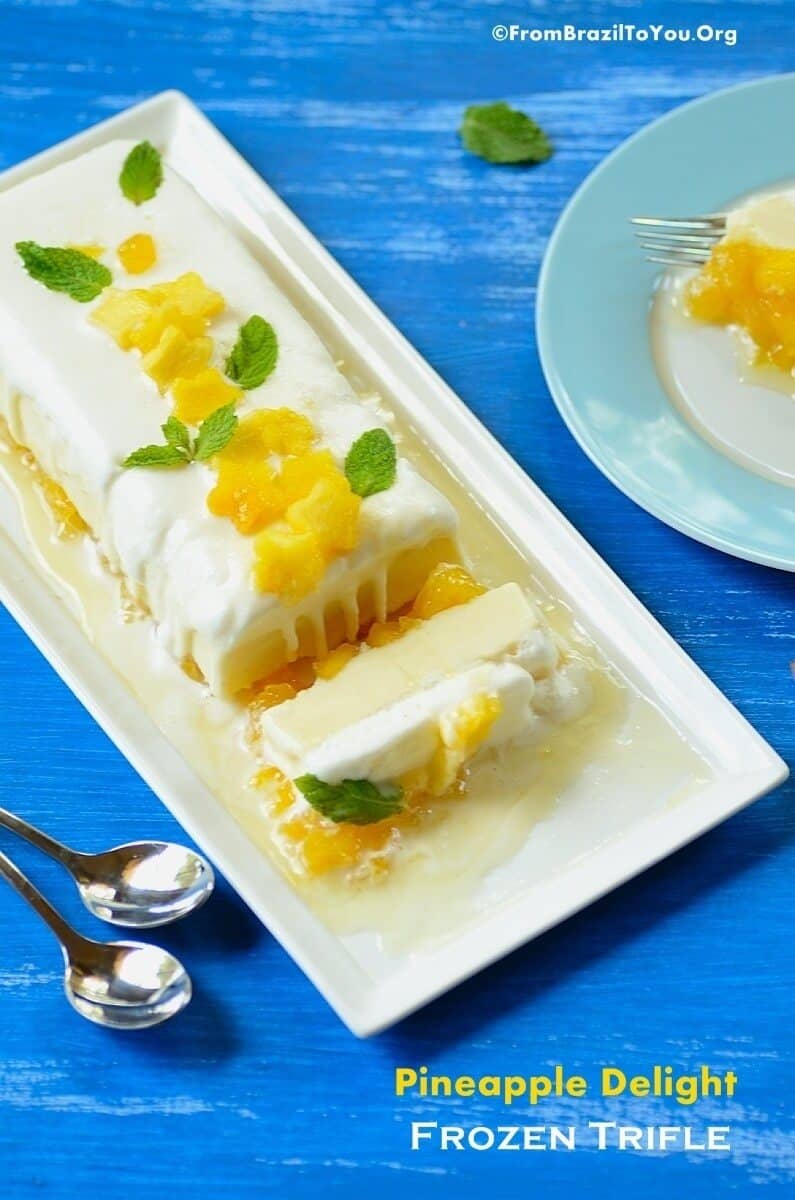 Yellow and White Pineapple Delight Frozen Trifle decorated with mint leaves, on a rectangular white dessert plate