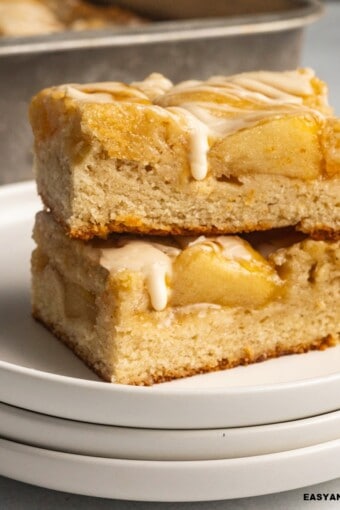 close up of two apple bars piled up topped with vanilla glaze.