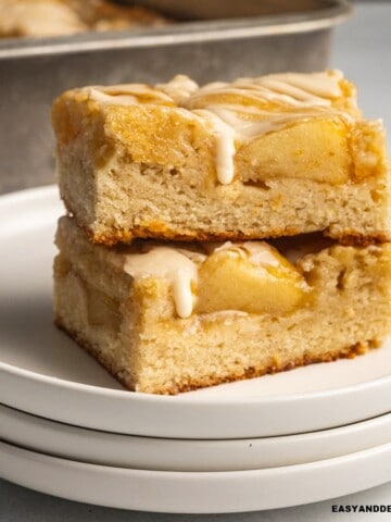 close up of two apple bars piled up topped with vanilla glaze.