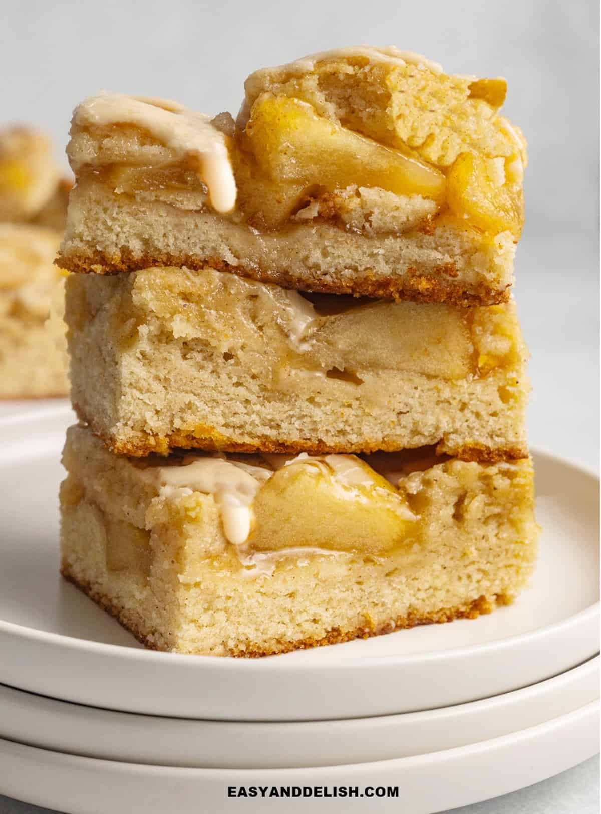 a stack of apple pie bars with glaze on top. 