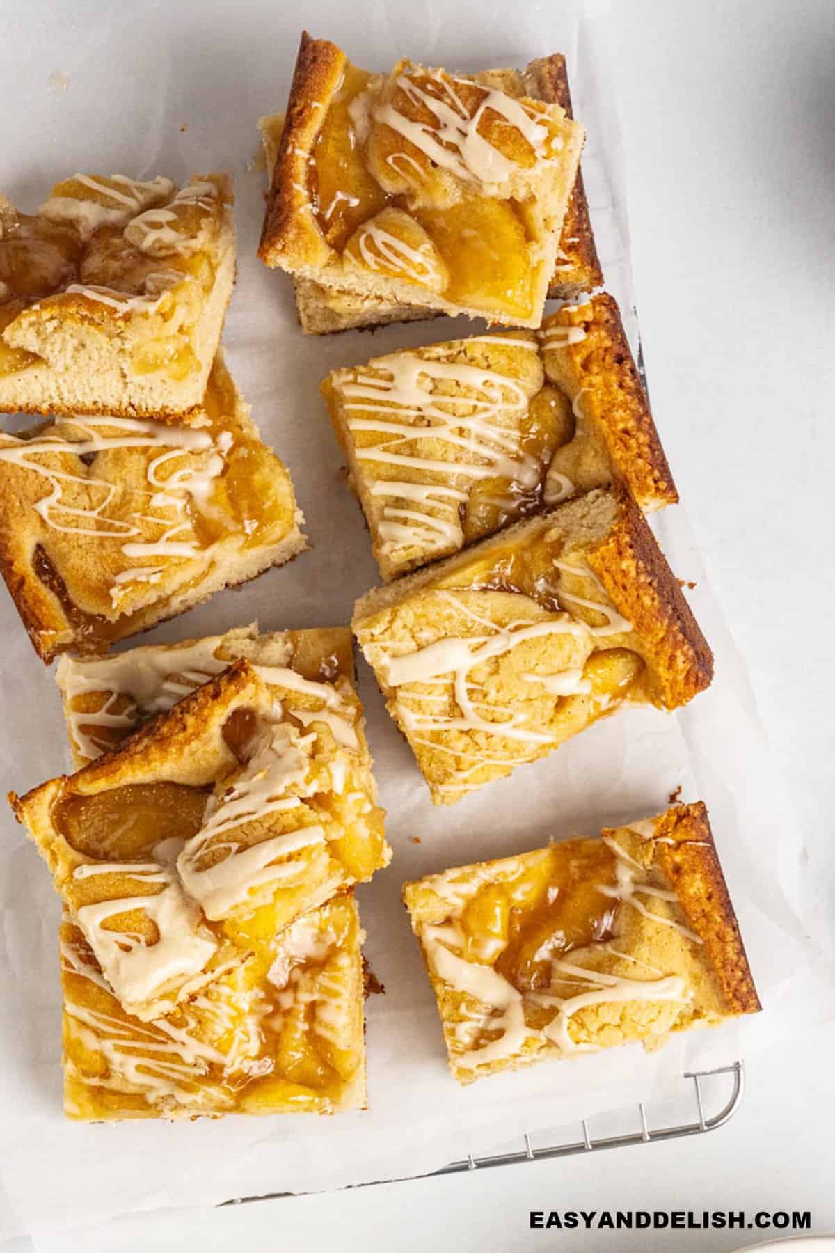 Several apple bars spread over a sheet of parchment paper.