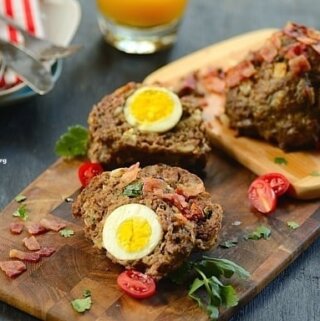 Meatloaf stuffed with boiled egg on a wood serving board