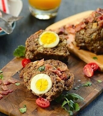 Meatloaf stuffed with boiled egg on a wood serving board
