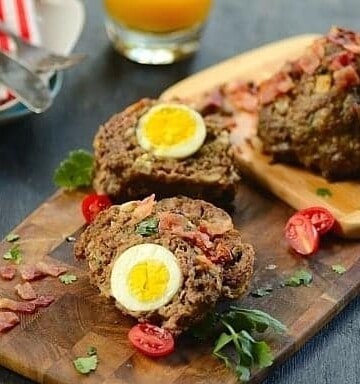 Meatloaf stuffed with boiled egg on a wood serving board