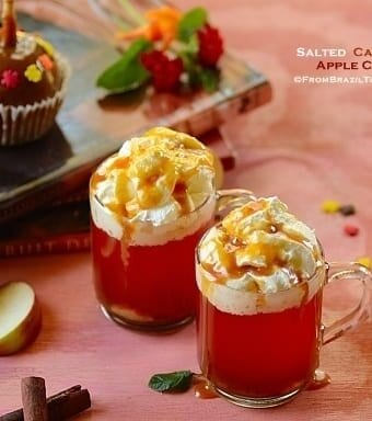 mugs of apple cider with garnishes on the sides