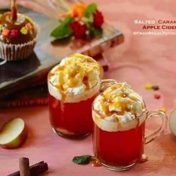 mugs of apple cider with garnishes on the sides
