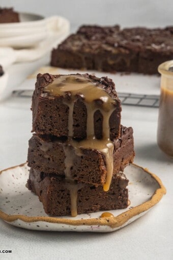 close up image of a pile of vegan sweet potato brownies with caramel on top.