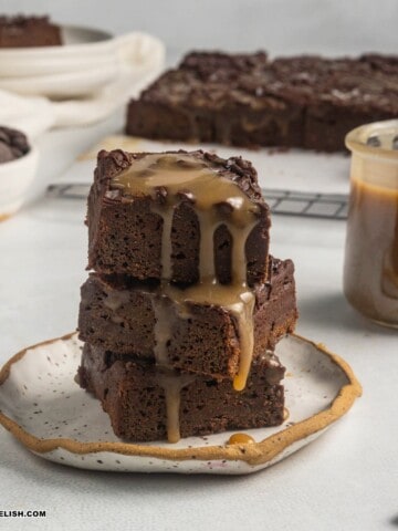 close up image of a pile of vegan sweet potato brownies with caramel on top.