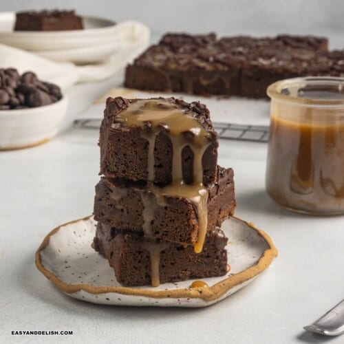 close up image of a pile of vegan sweet potato brownies with caramel on top.