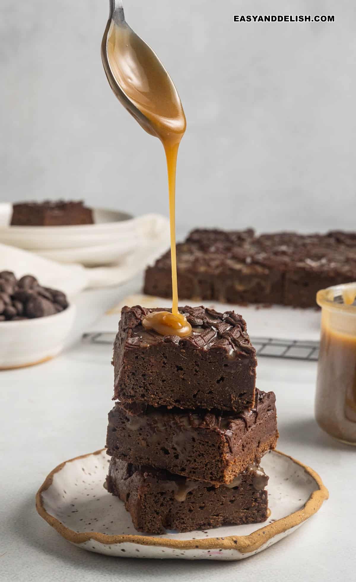 a pile of sweet potato brownies with a spoon of caramel drizzled on top. 