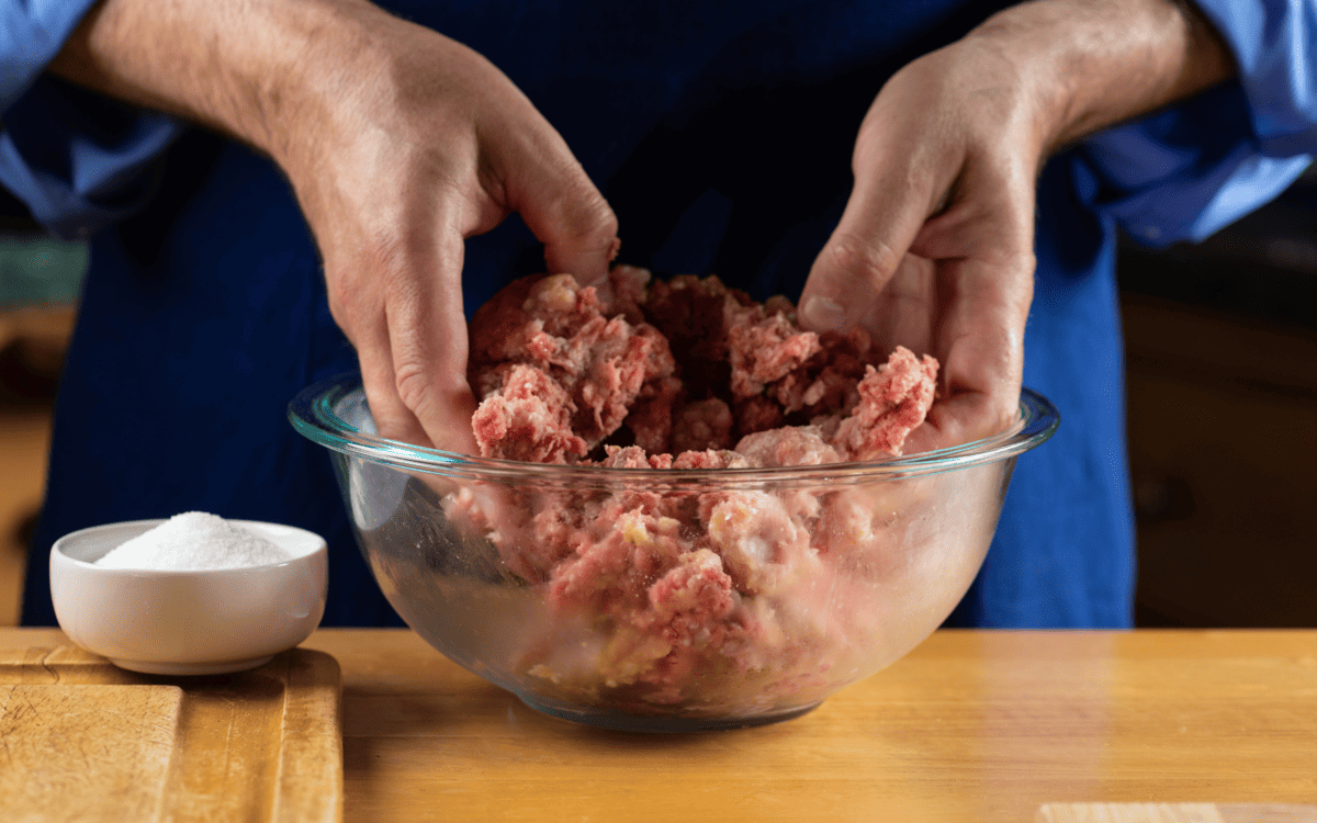 Mixing ingredients of the German meatloaf in a bowl using hands.