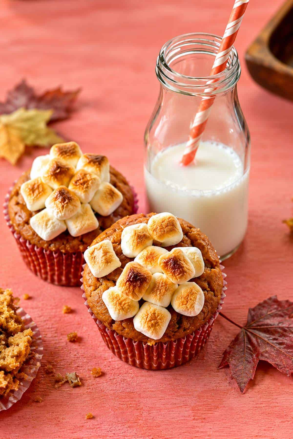 Candied sweet potato cupcakes topped with toasted marshmallows and served with a glass of milk.