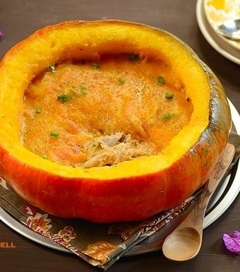 A half pumpkin shell filled with chicken stew topped with melted cheese