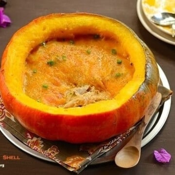 A half pumpkin shell filled with chicken stew topped with melted cheese