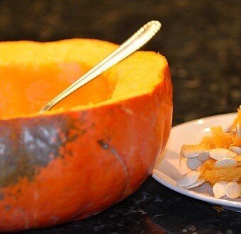 pumpkin seeds being scooped out with a spoon onto a plate