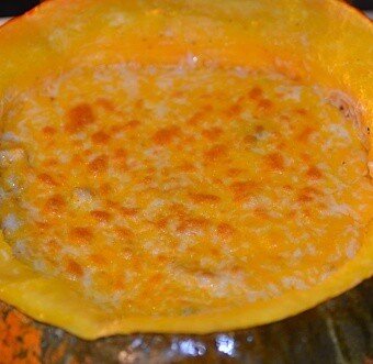 pumpkin shell filled with stew and topped with shredded cheese that has been broiled