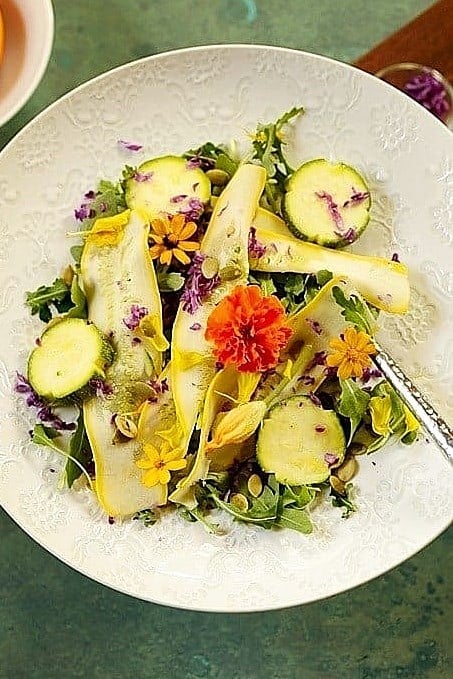 Fall salad with zucchini, mixed greens, edible flowers, and a light dressing for Thanksgiving.
