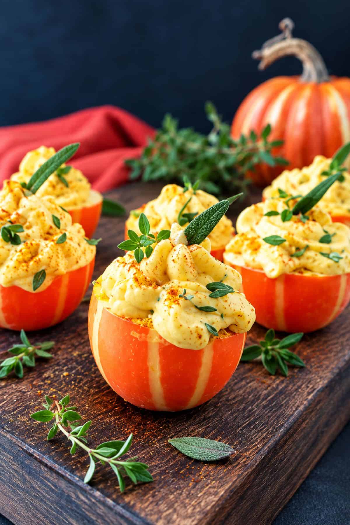 Curried pumpkin deviled eggs garnished with fresh herbs for a Thanksgiving appetizer.