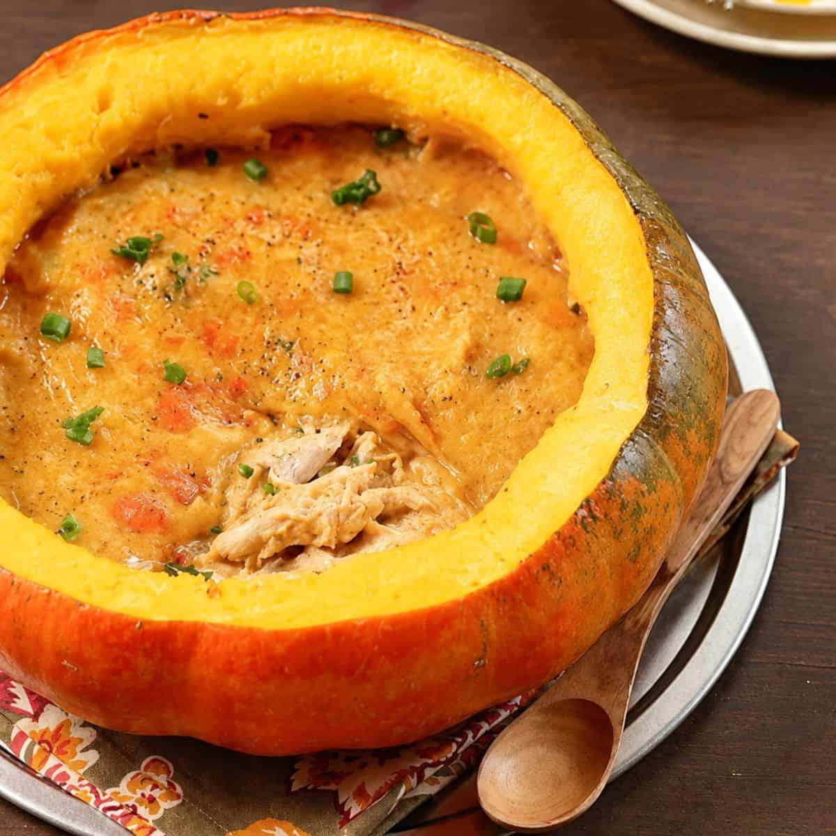 Pumpkin chicken stew served inside a roasted pumpkin shell with herbs.
