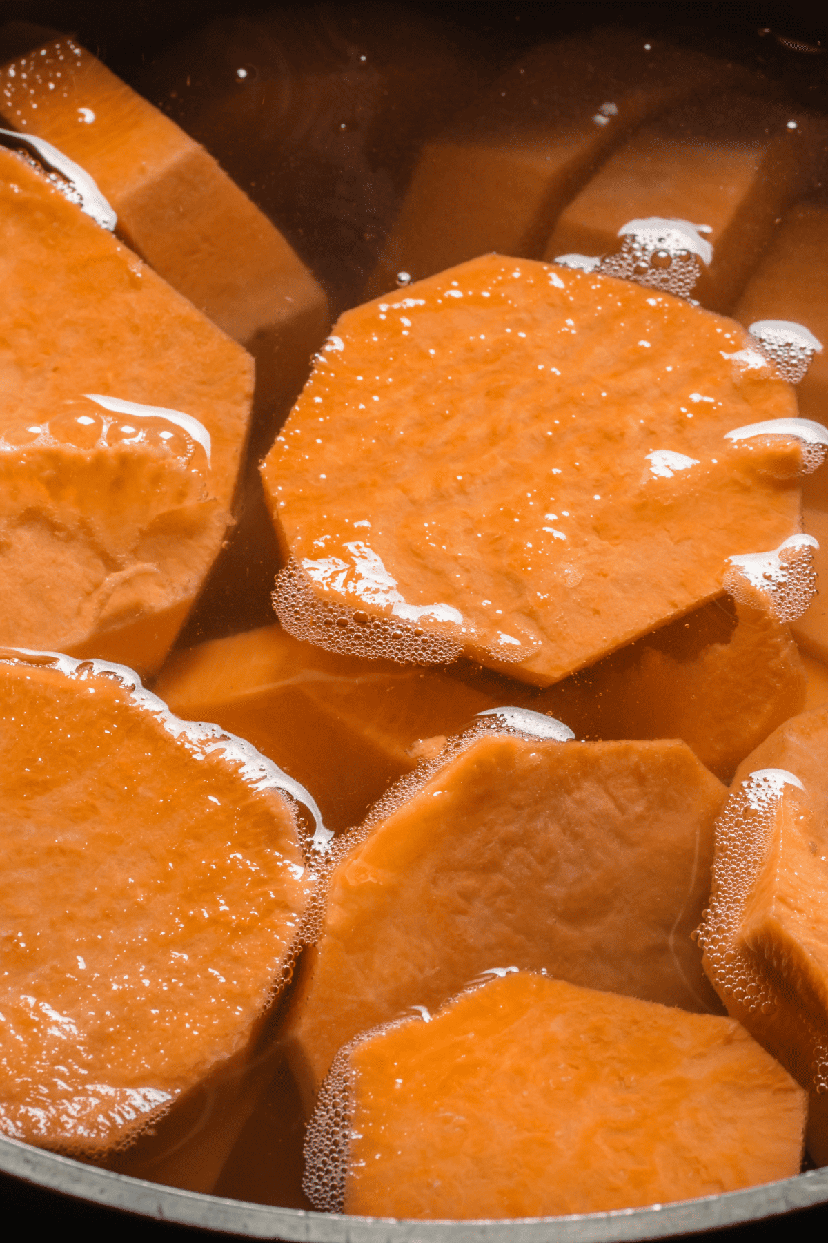 Sliced root vegetable cooking in a pot of boiling water. 