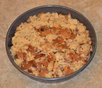 panettone cubes spread out in a dish over the layered fruits