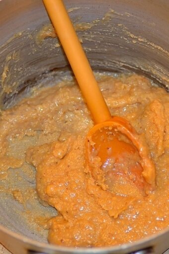 dough being stirred in a metal pot with a wooden spoon