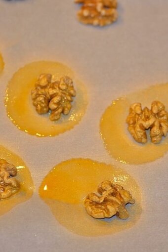 walnuts that were sprayed with Wilton gold color mist food spray sitting on parchment paper