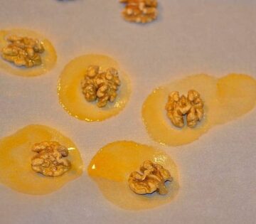 walnuts that were sprayed with Wilton gold color mist food spray sitting on parchment paper