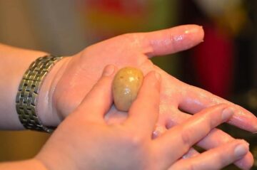 ball of dough held in the palm of one hand and slightly pinched between 2 fingers of the other hand