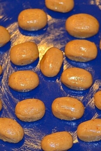 several shaped balls of candy dough set on a greased blue plate