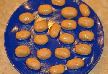 several shaped balls of candy dough set on a greased blue plate